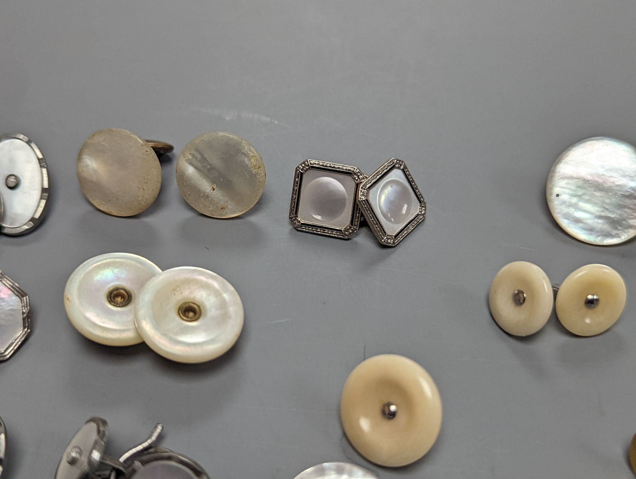 Two pairs of 18ct and mother of pearl cufflinks, one set with sapphires, both with gilt metal associated links, together with a quantity of base metal buttons, cufflinks, studs, etc.